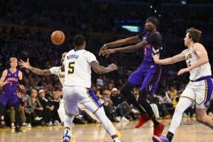 Toronto Raptors forward Chris Boucher (25) passes the ball against Los Angeles Lakers guards Cam Reddish (5), Austin Reaves (15), and D’Angelo Russell (1)