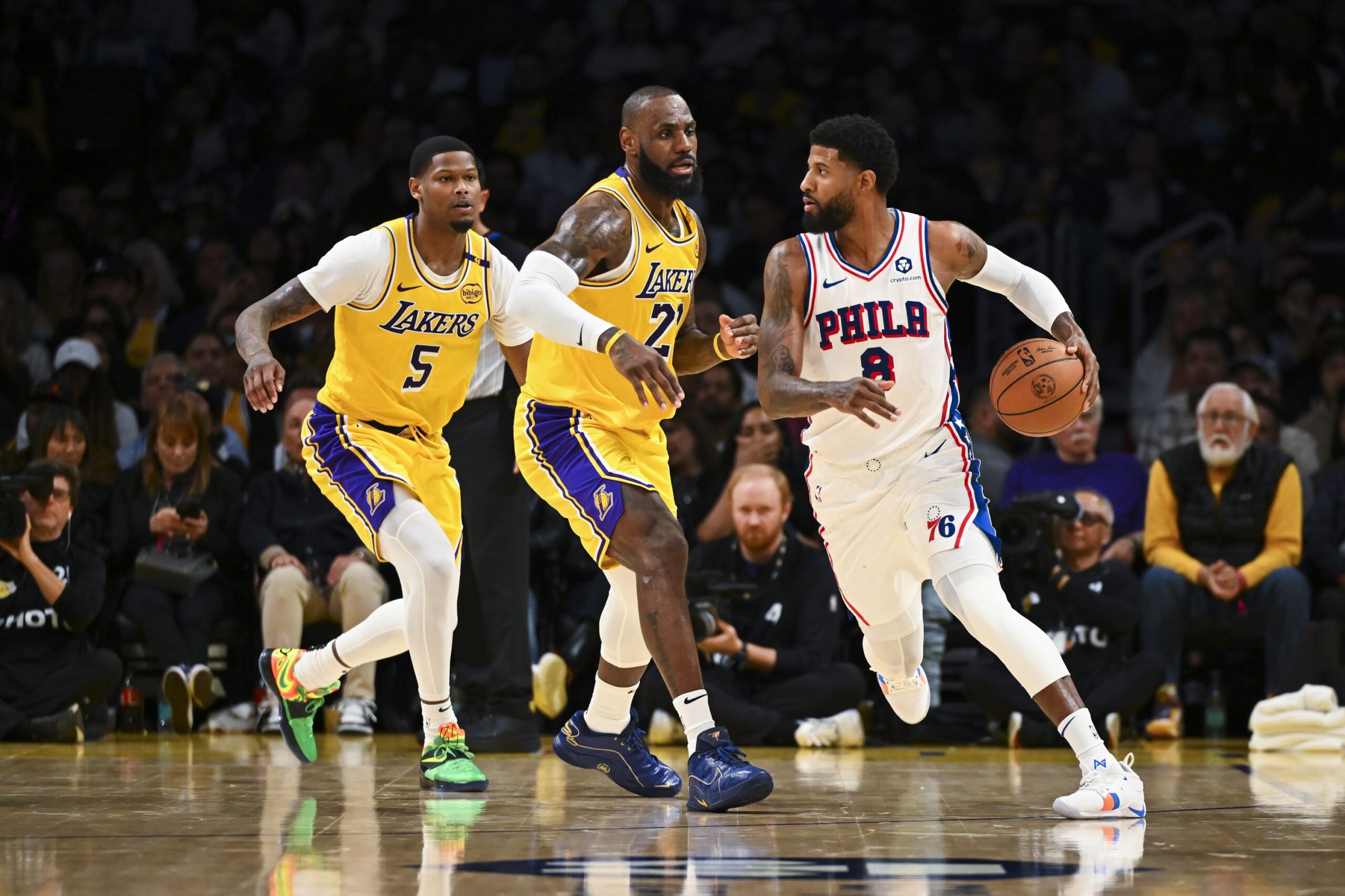 Nov 8, 2024; Los Angeles, California, USA; Philadelphia 76ers forward Paul George (8) looks to pass against Los Angeles Lakers forward LeBron James (23) and forward Cam Reddish (5) during the second half at Crypto.com Arena. Mandatory Credit: Jonathan Hui-Imagn Images