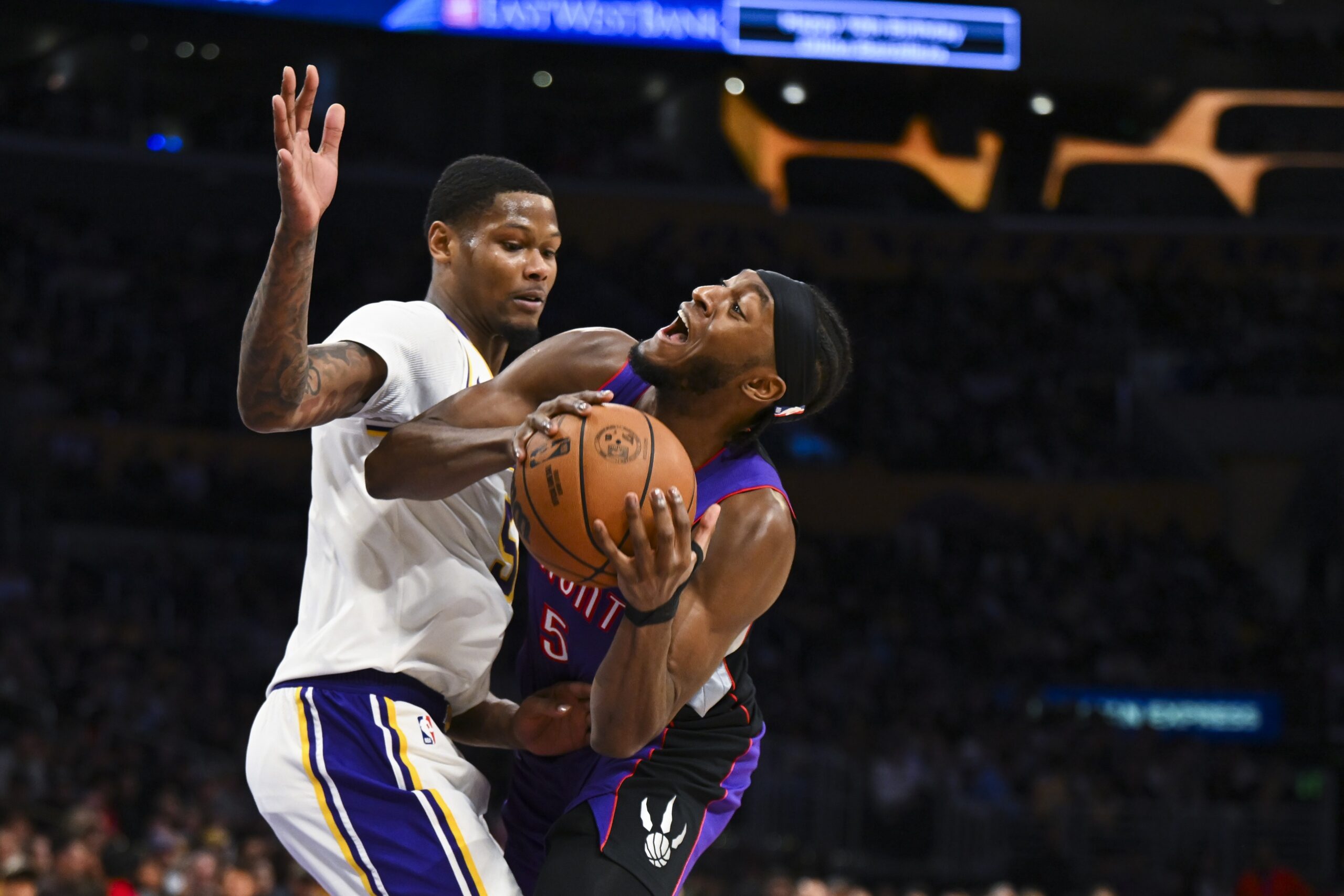 Nov 10, 2024; Los Angeles, California, USA; Los Angeles Lakers forward Cam Reddish (5) blocks Toronto Raptors guard Immanuel Quickley (5) during the second half at Crypto.com Arena. Mandatory Credit: Jonathan Hui-Imagn Images